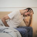 young man in sleepwear suffering from headache in morning